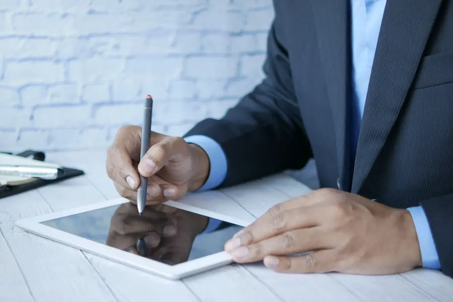 Hand unterschreibt mit einem Stift auf einem Tablet