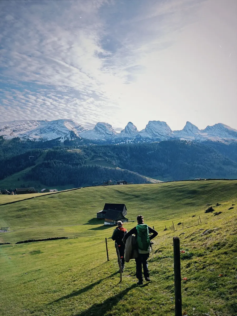 Zwei Wanderer auf einer Alpweide mit Blick auf die verschneiten Churfirsten